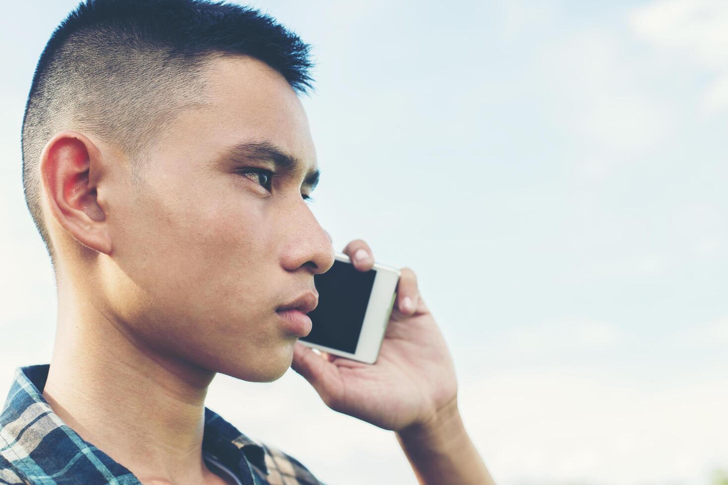 Young man talking on the phone and standing on the grass in the park. photo