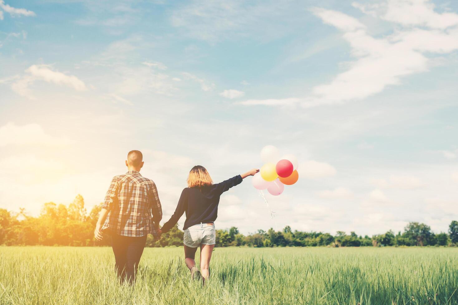 parte posterior de la feliz pareja asiática joven sosteniendo globo y caminar juntos. foto