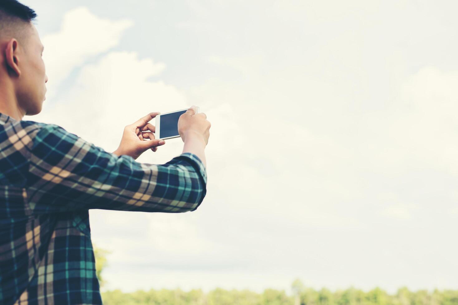 Young hipster man using smartphone taking the landscape photography. photo