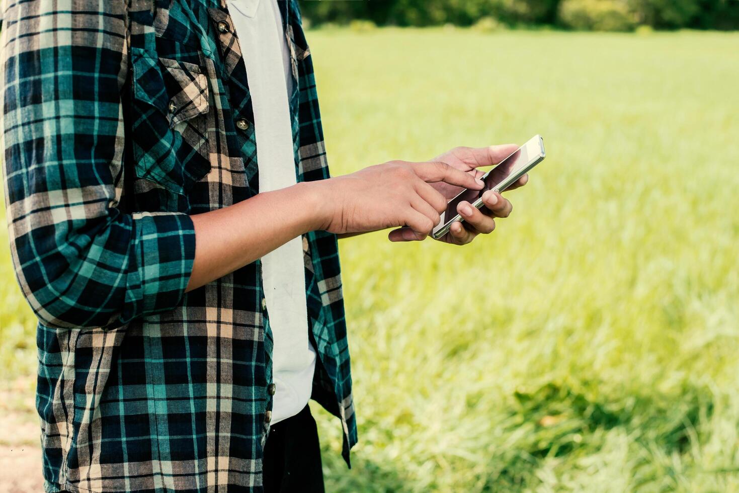 Primer plano de manos de hombre hipster usando su teléfono inteligente al aire libre en el parque foto