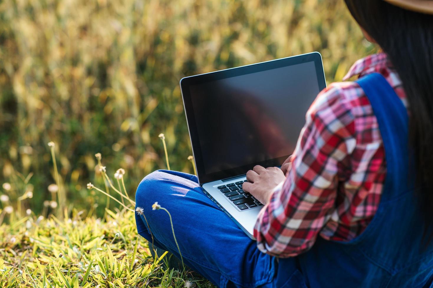 Smart woman farmer looking at barley field with laptop computer photo
