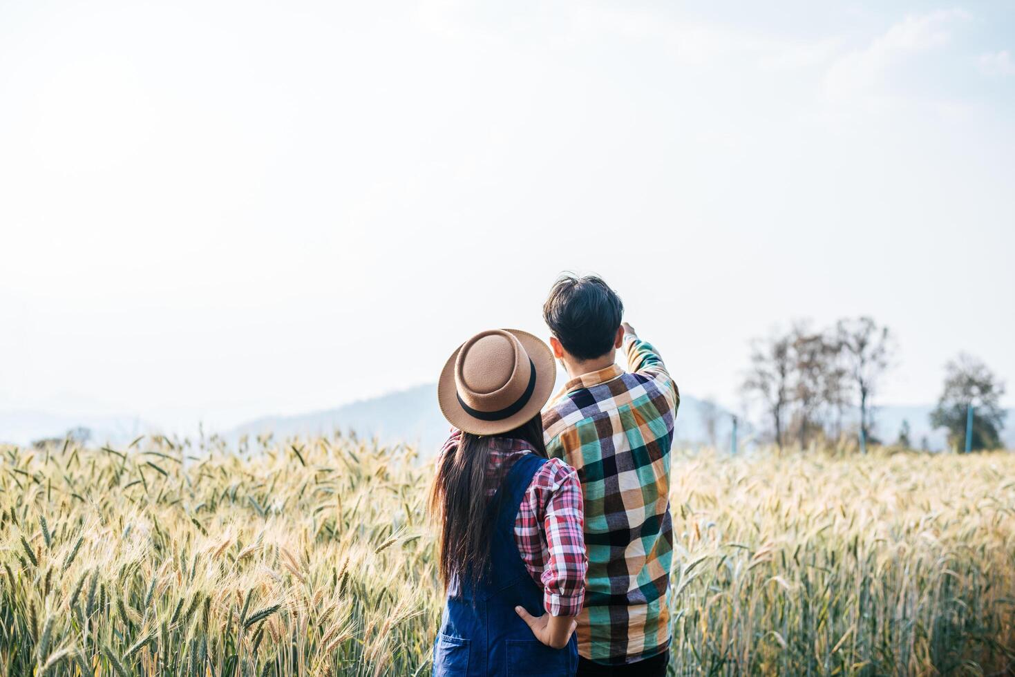 Farming couple looking out at barley field in harvesting season photo