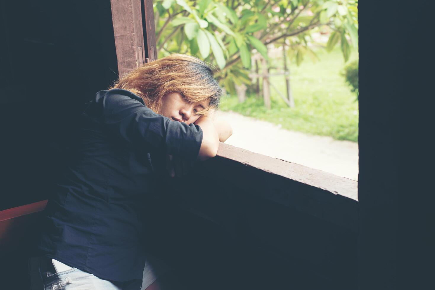 Sad woman sitting on bench beside window photo