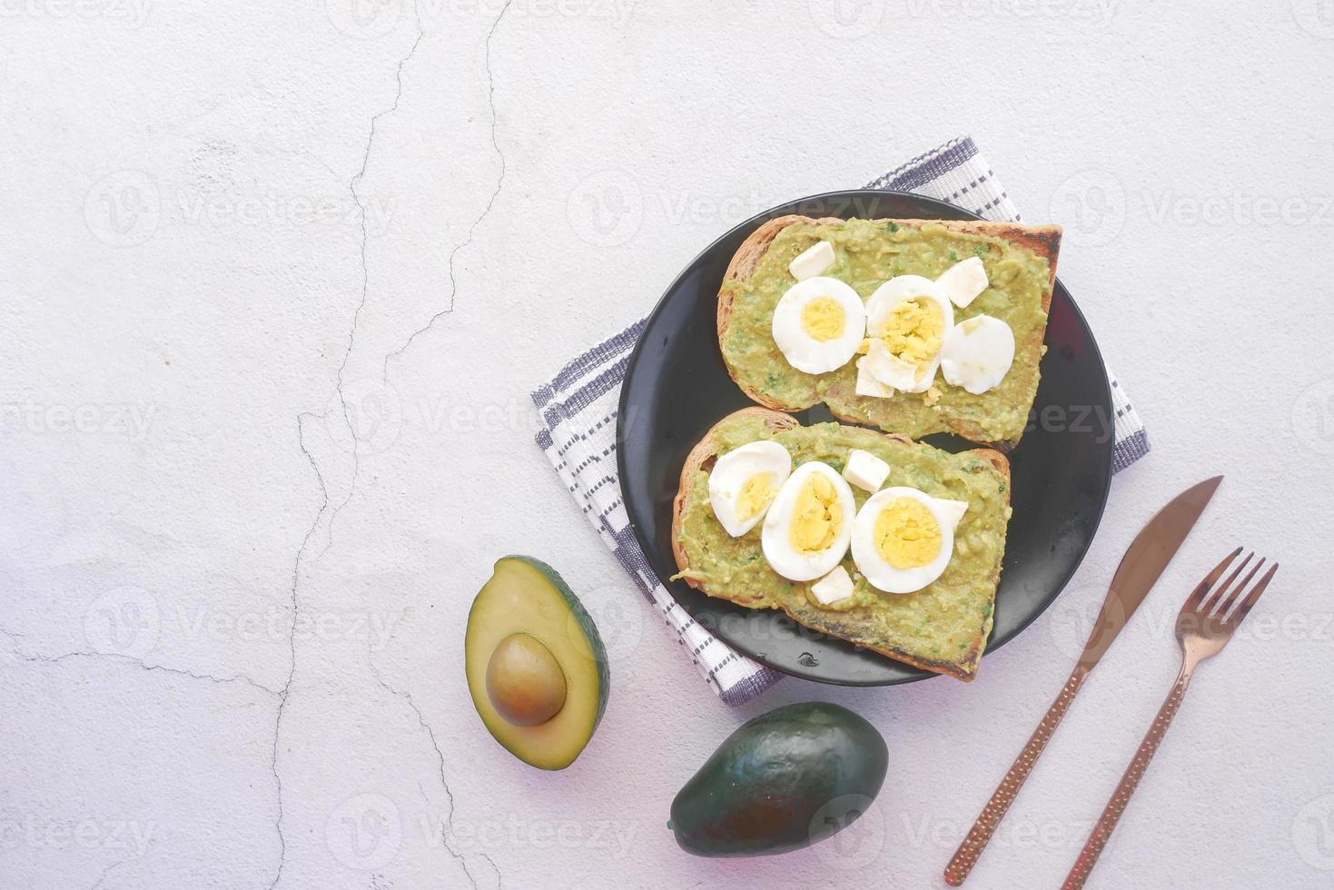 Aguacate y huevo en una rebanada de pan integral sobre fondo blanco. foto