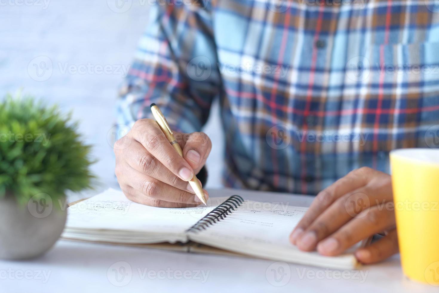 cerca de la mano del hombre escribiendo en el Bloc de notas. foto