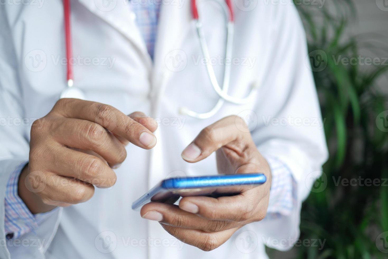 médico en bata blanca con un teléfono inteligente. foto