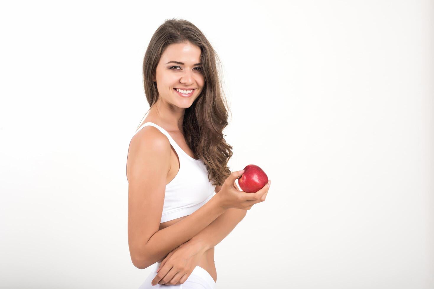 Belleza mujer sosteniendo manzana roja mientras aislado en blanco foto