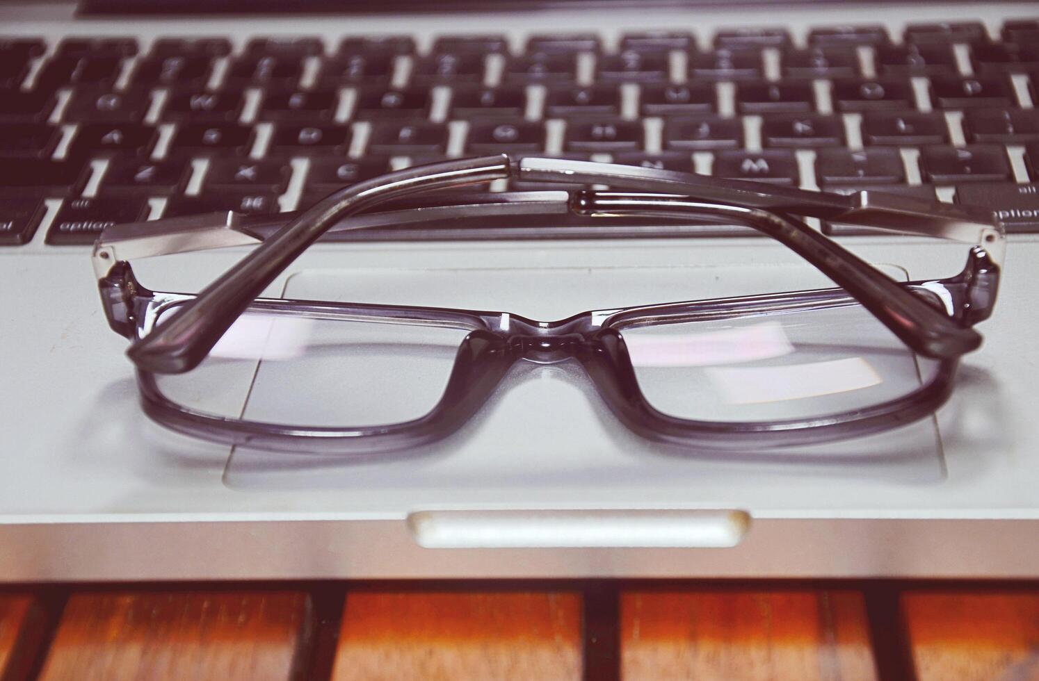 Close up eye glasses, office computer on working desk, photo