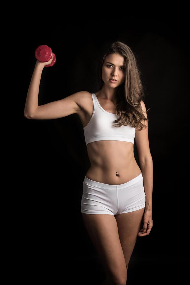 Young beautiful woman doing physical exercises with dumbbells photo