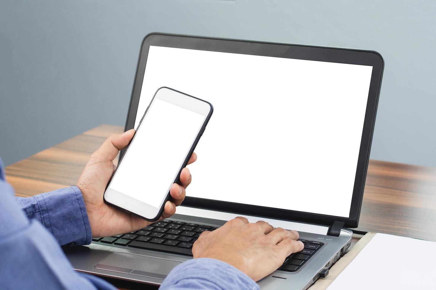 Primer plano de la mano con un teléfono inteligente móvil en el trabajo de oficina, la pantalla del teléfono simula una copia de especificaciones foto
