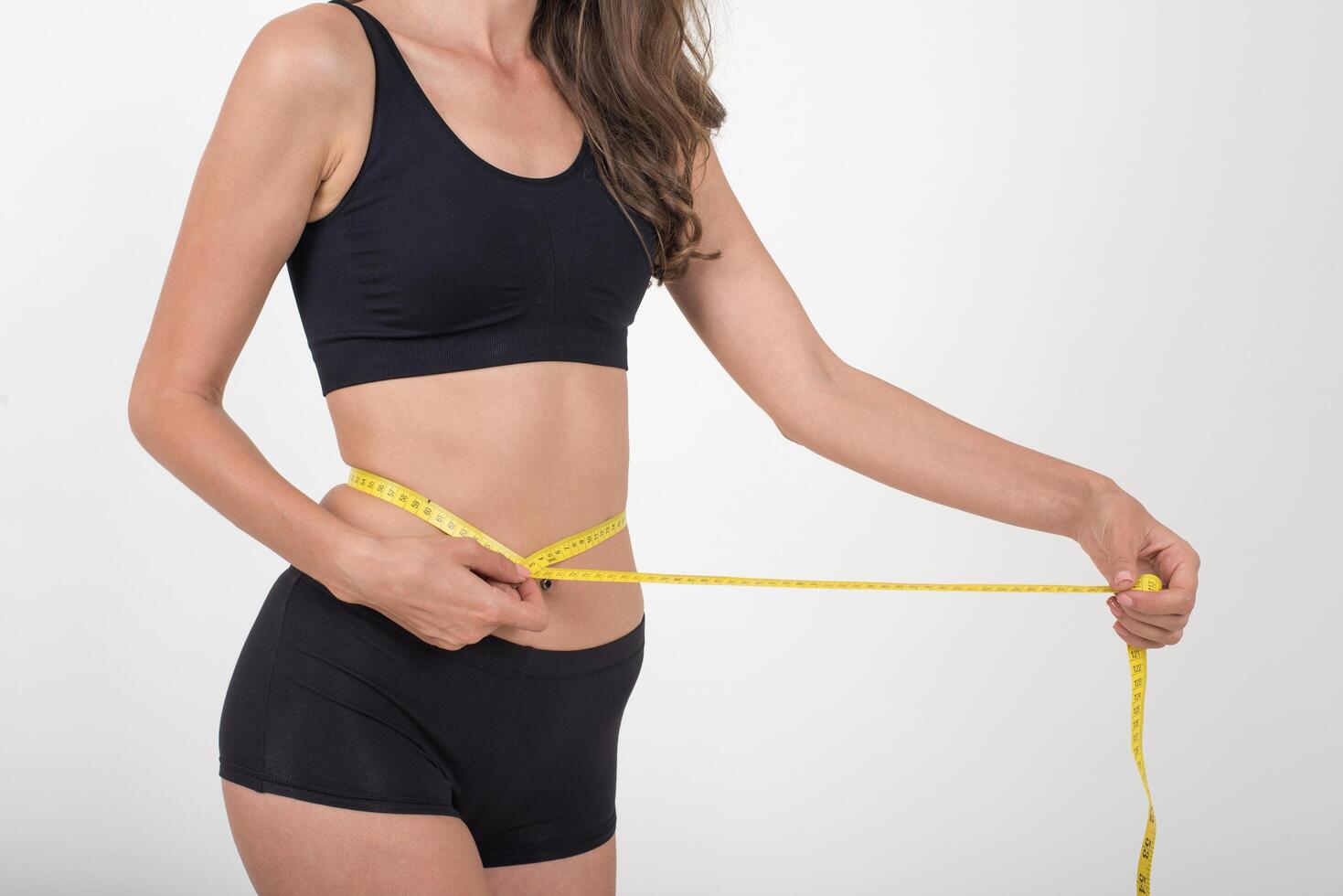 Portrait of beautiful young woman measuring her figure size with tape measure photo