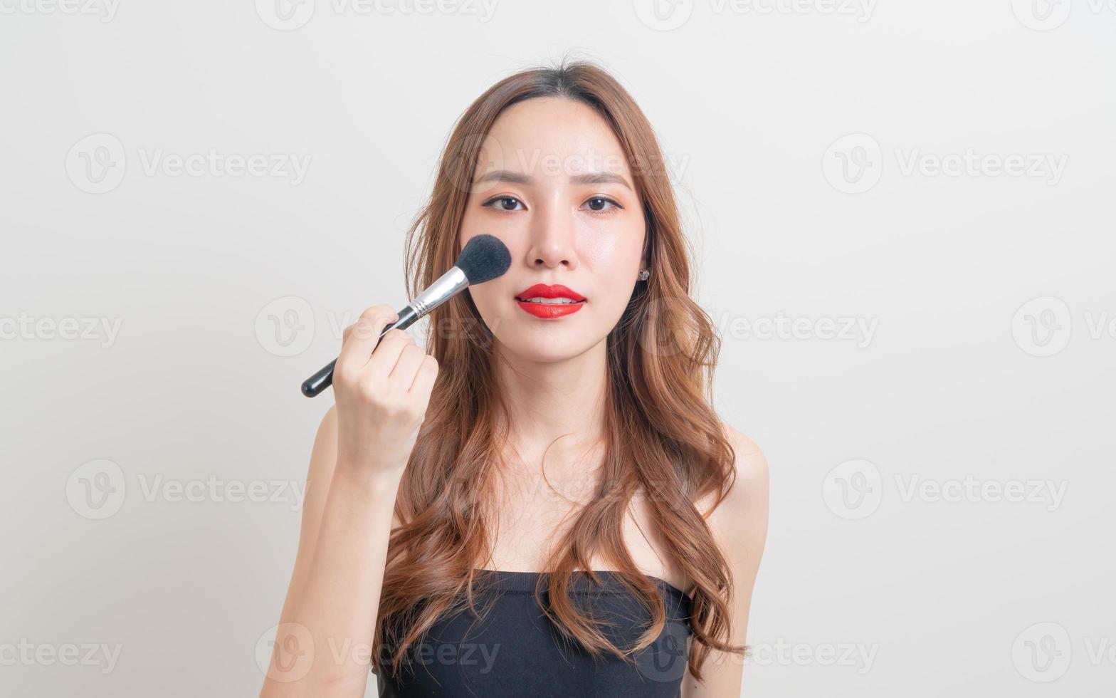 Retrato hermosa mujer asiática con pincel de maquillaje sobre fondo blanco. foto