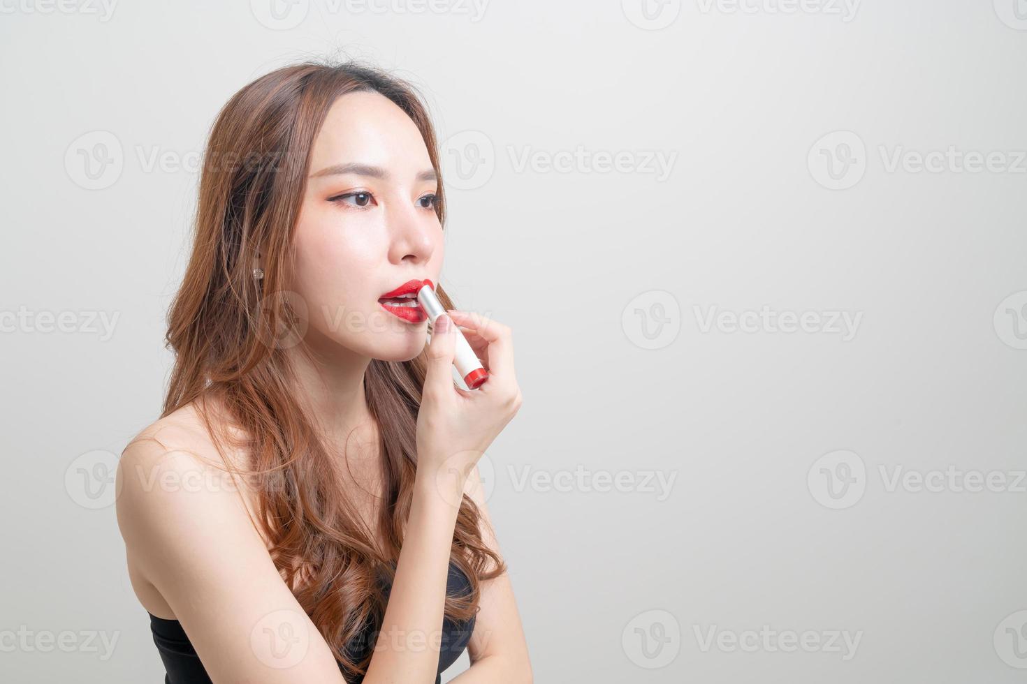 Retrato hermosa mujer asiática haciendo y usando lápiz labial rojo sobre fondo blanco. foto