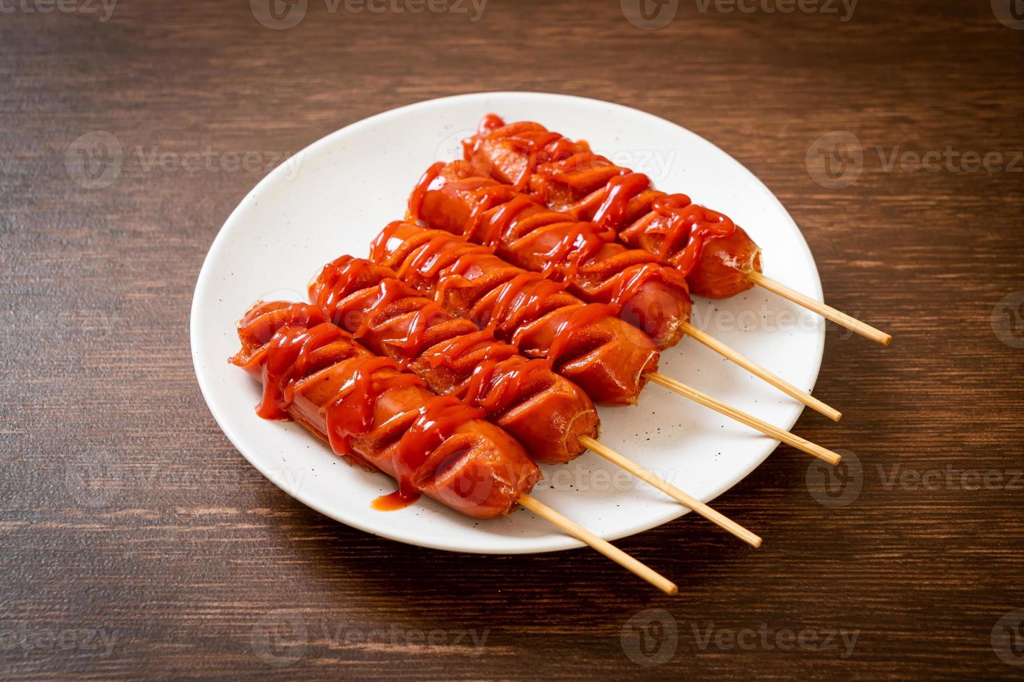 Fried sausage skewer with ketchup on white plate photo