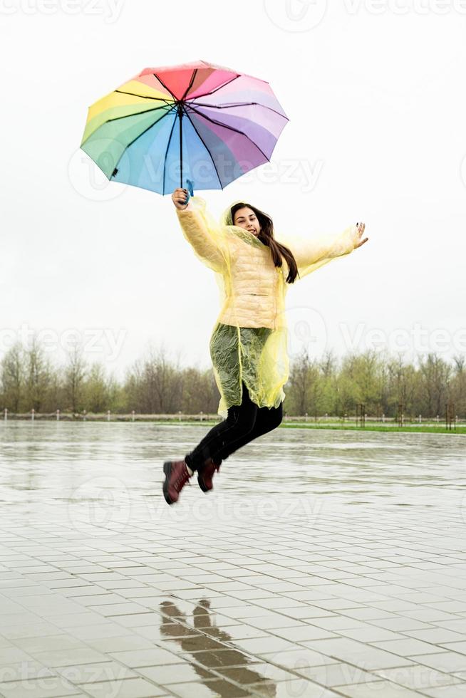 Beautiful brunette woman holding colorful umbrella out in the rain photo