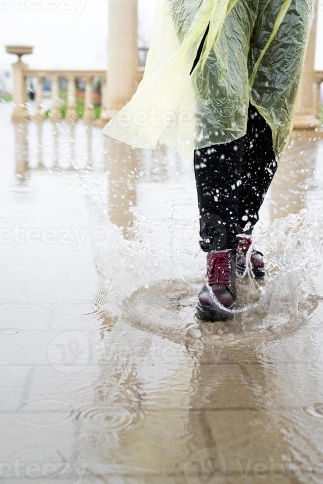 mujer jugando bajo la lluvia, saltando en charcos con salpicaduras foto