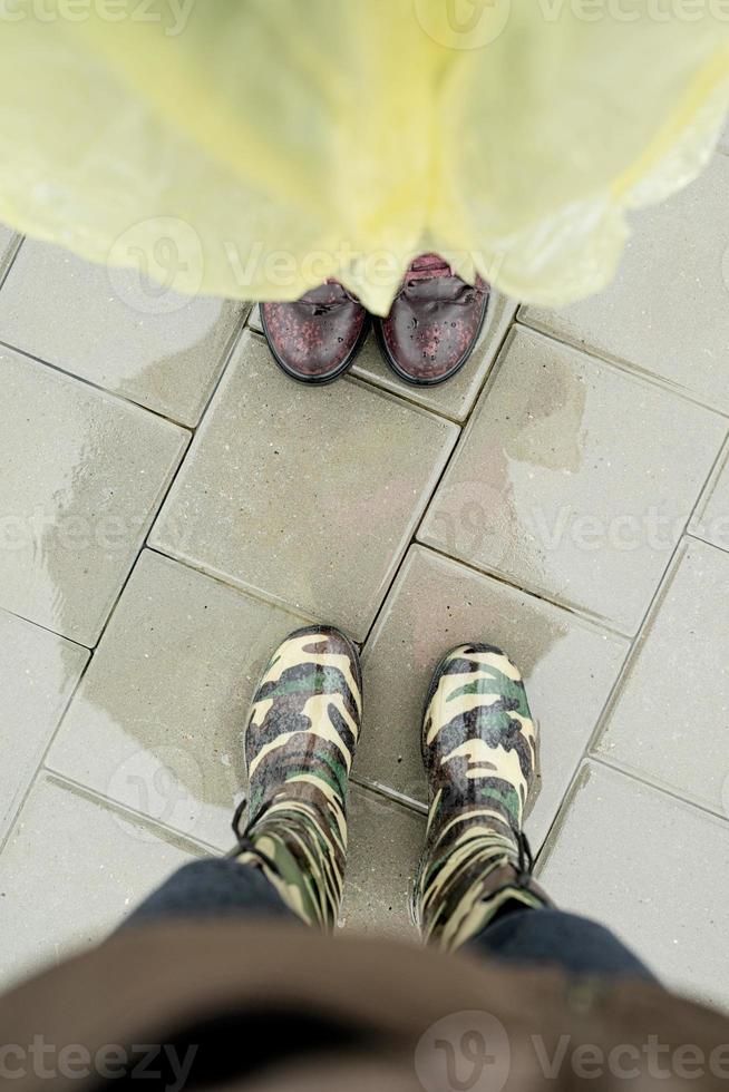 Vista superior de dos pares de pies femeninos de pie en charcos en días lluviosos foto