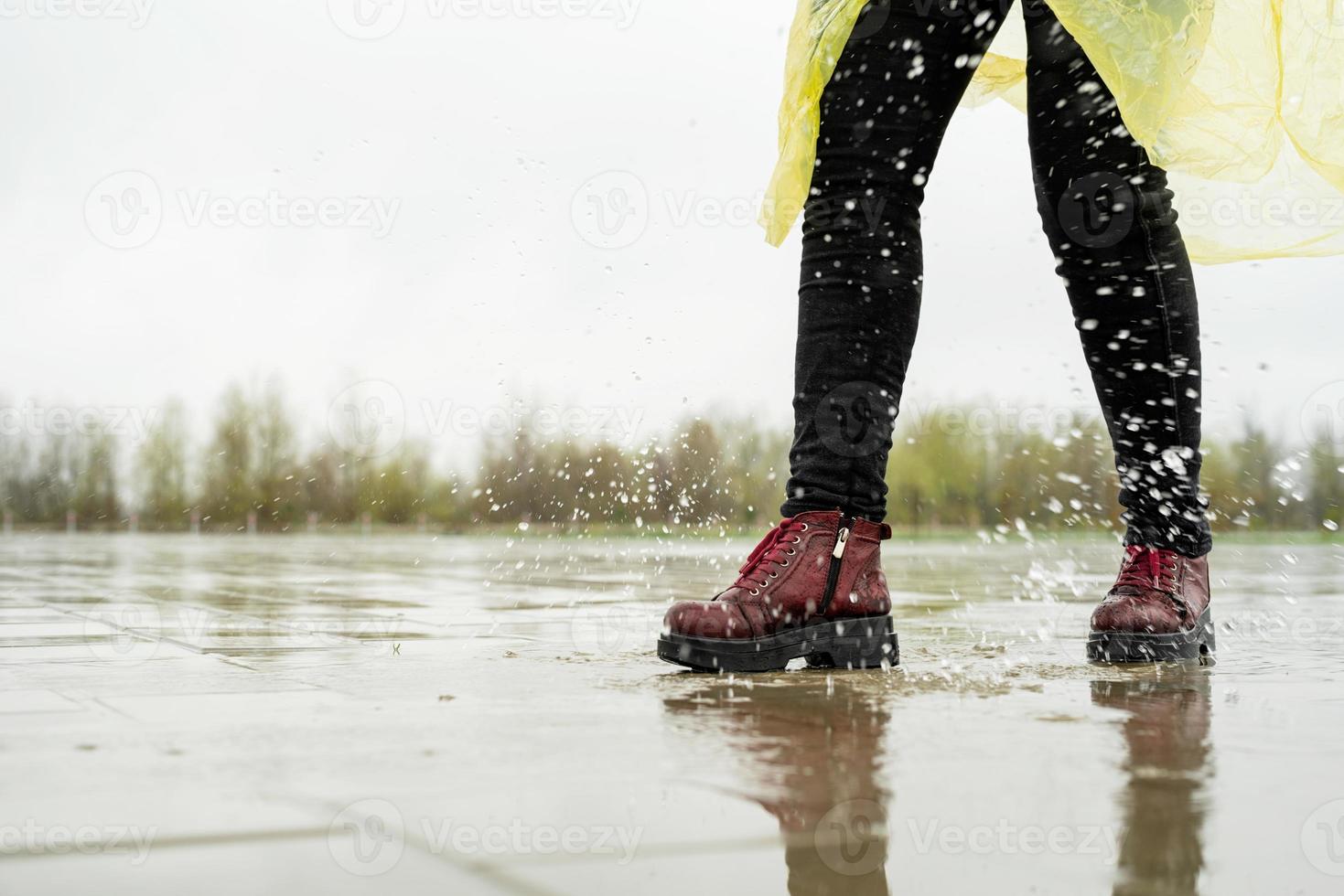 mujer jugando bajo la lluvia, saltando en charcos con salpicaduras foto