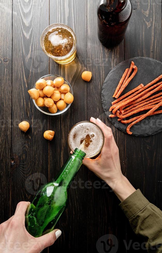 Verter la cerveza de la botella en vidrio, fondo de madera negra foto