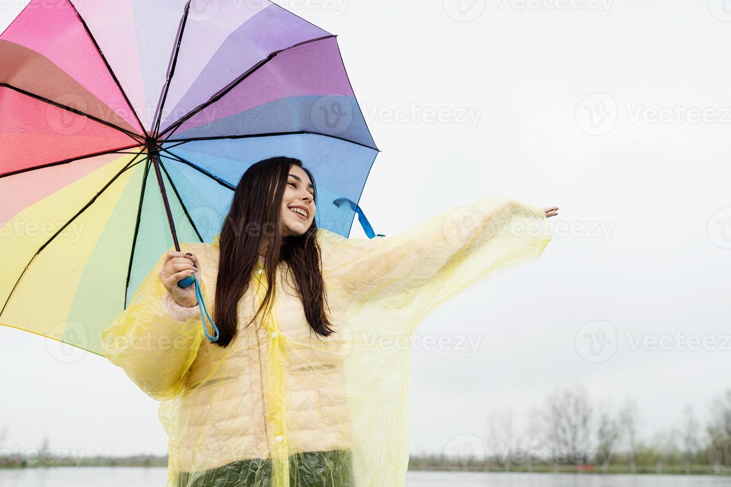 Hermosa mujer morena sosteniendo coloridos paraguas bajo la lluvia foto