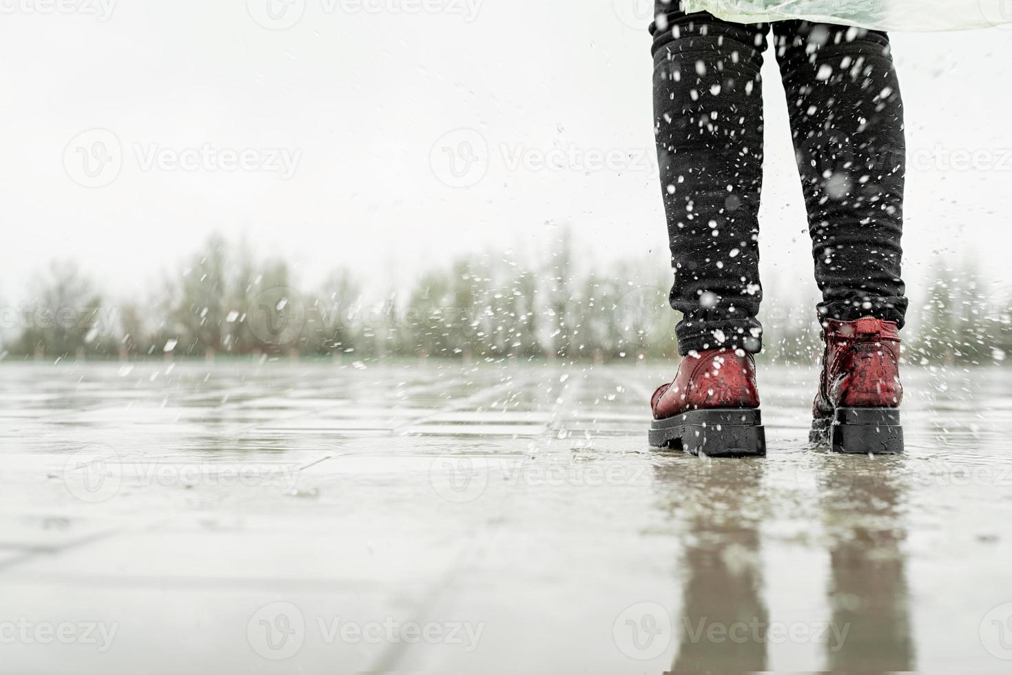 mujer jugando bajo la lluvia, saltando en charcos con salpicaduras foto