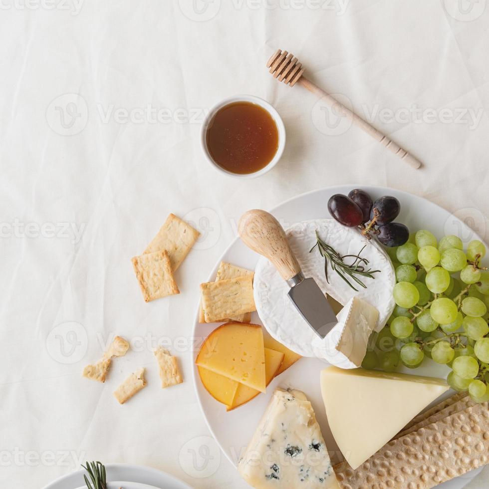 Cheese plate assortment served with honey, grapes, bread and rosemary photo