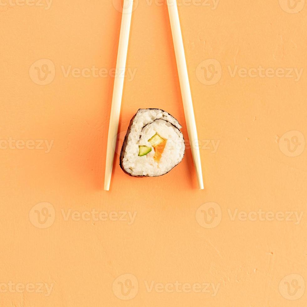Sushi rolls and chopsticks isolated on orange background photo
