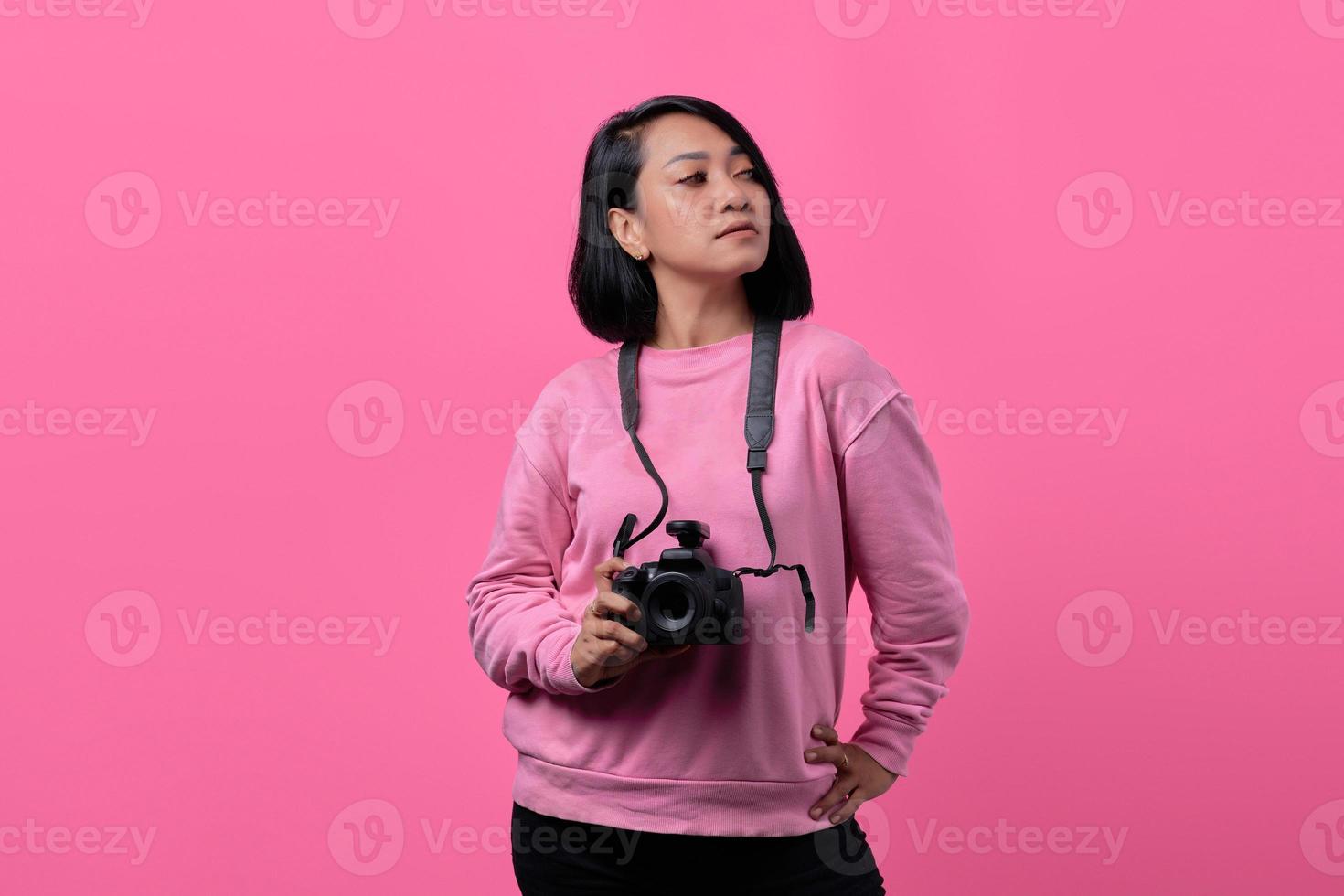 Young woman holding camera with flat expression photo