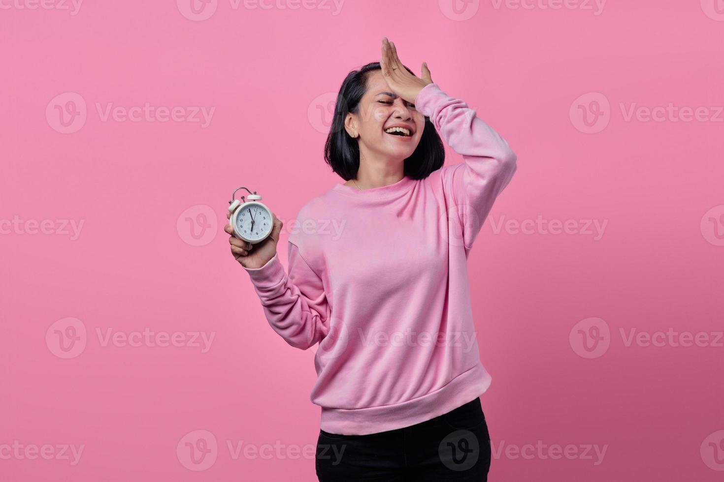 Conmocionada joven sostiene el despertador blanco en la mano foto