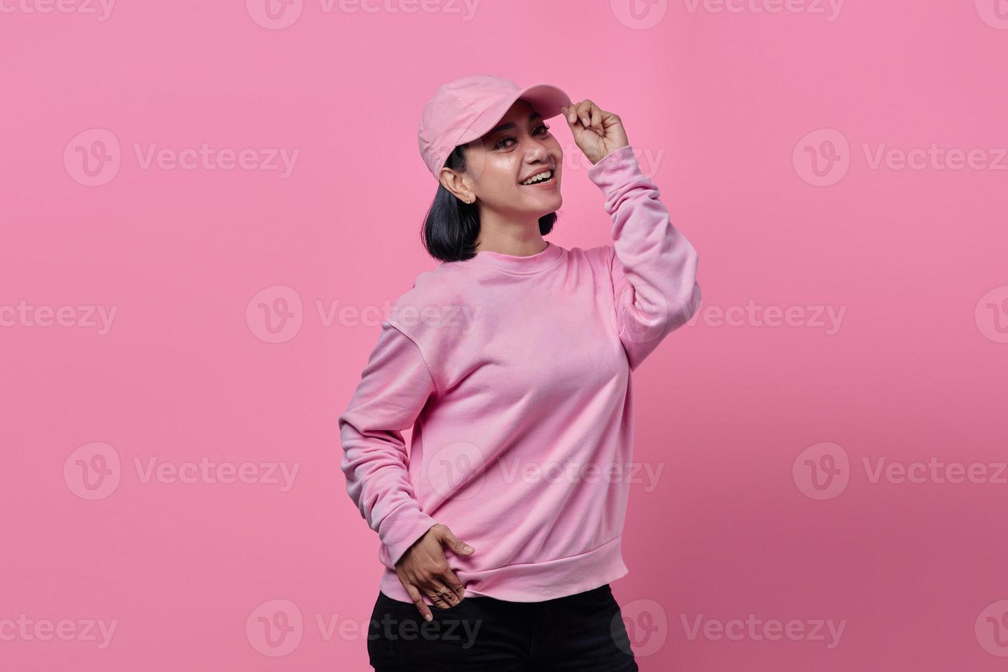 Hermosa mujer asiática vistiendo chaqueta sonriendo con las manos sosteniendo el sombrero foto