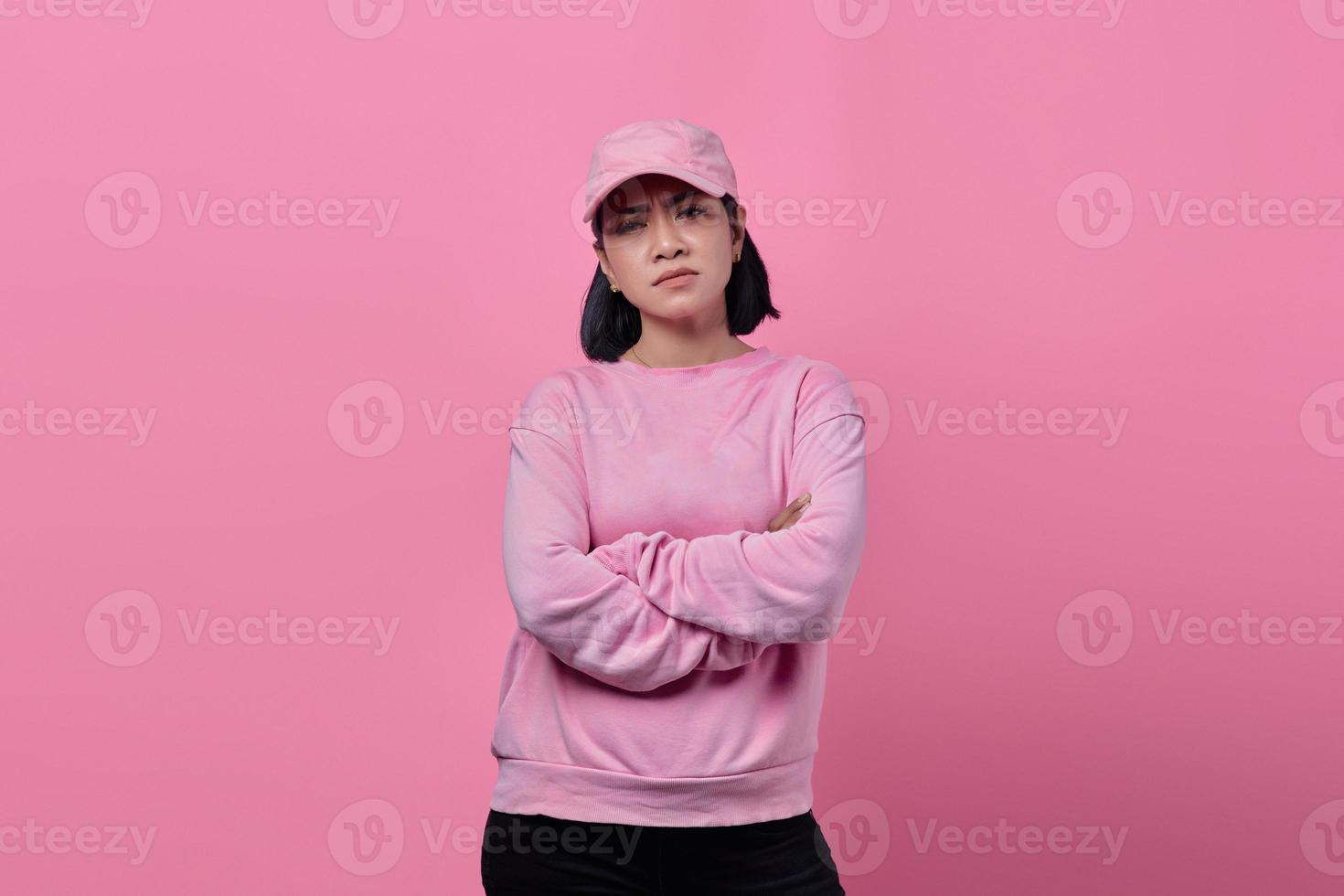 Retrato de mujer enojada de pie con los brazos cruzados sobre fondo de color rosa foto