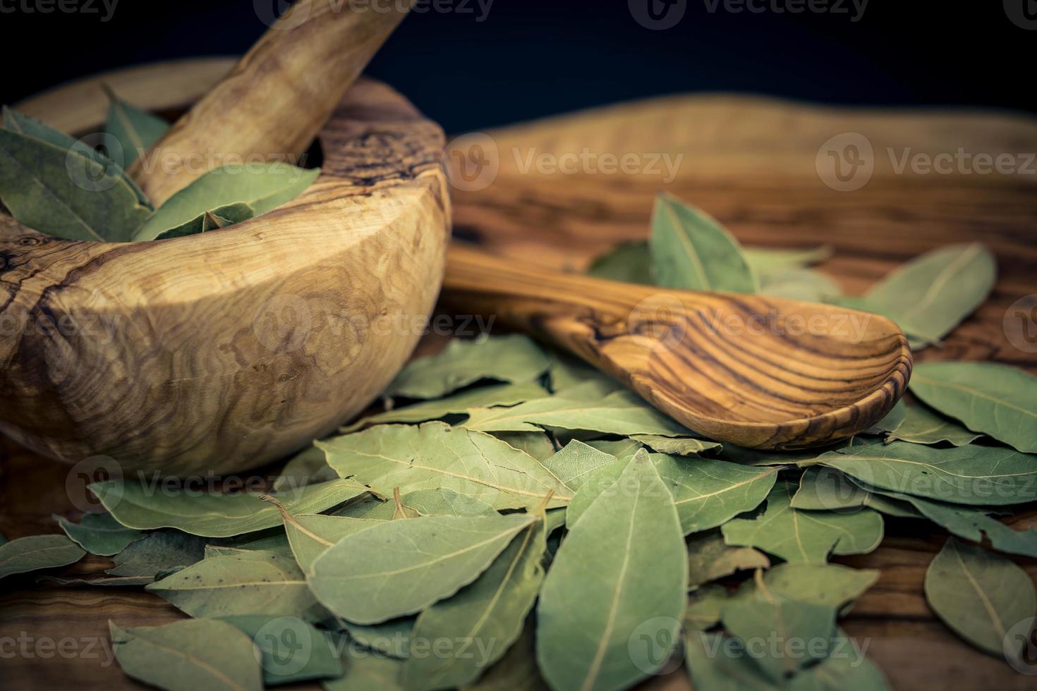 hojas de laurel y bayas de enebro en madera de olivo foto