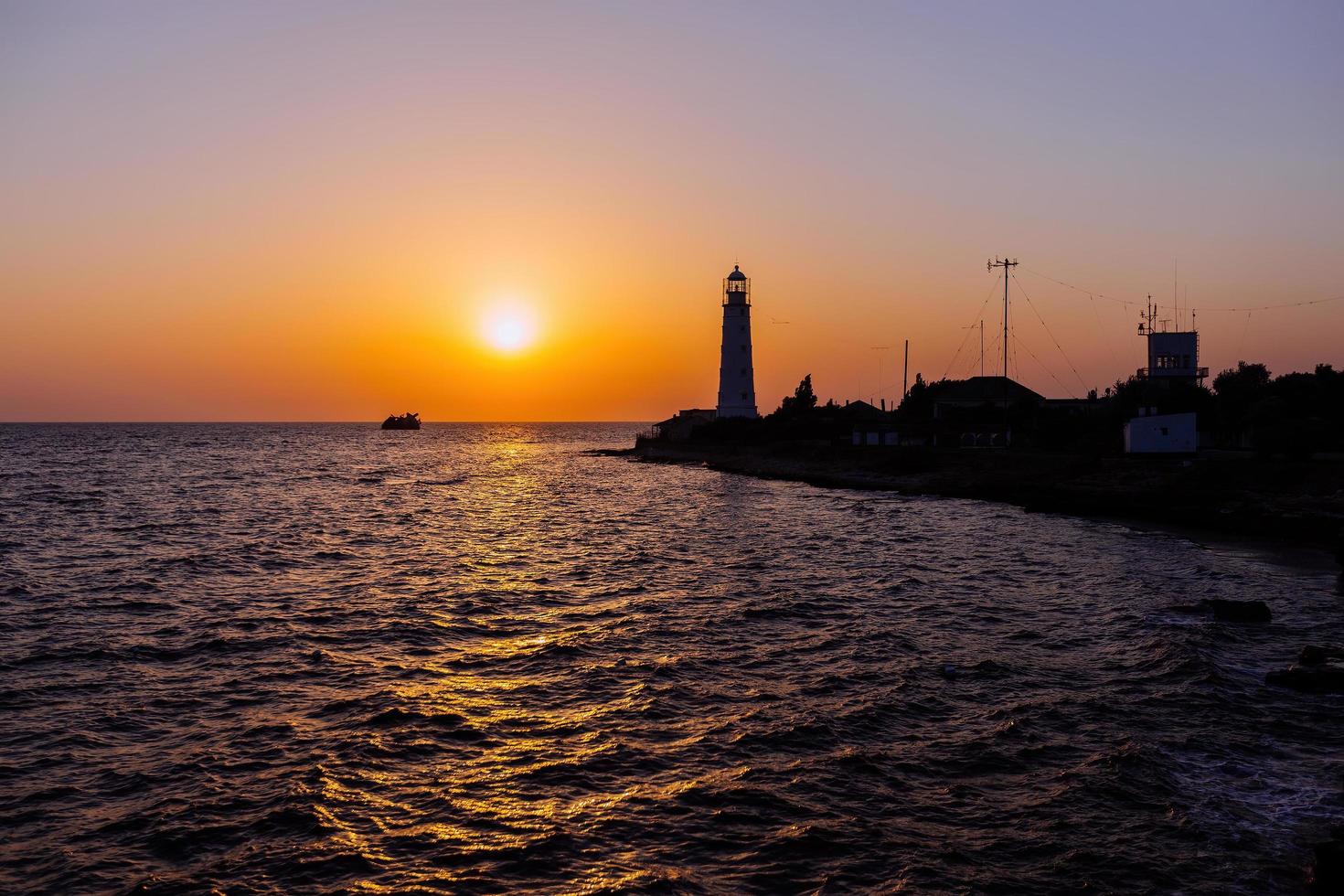 Lighthouse on the sea coast at sunset photo