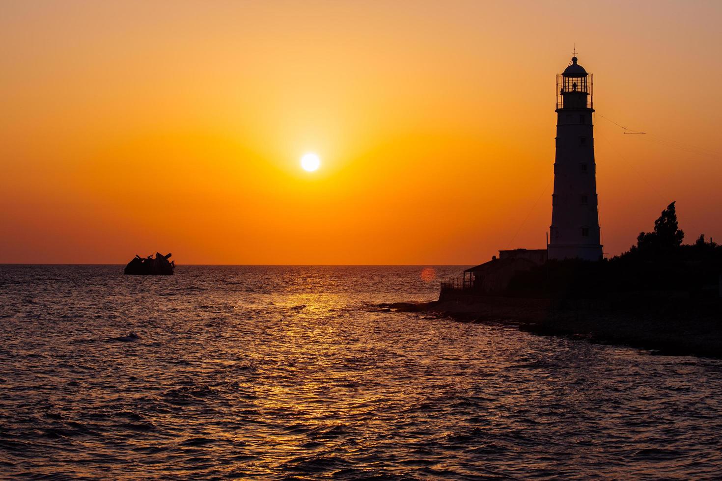 faro en la costa del mar al atardecer foto