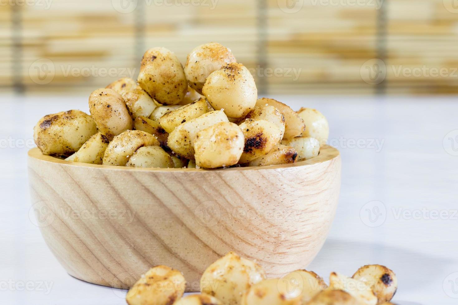 Macadamia horneada con salazón en recipiente de madera sobre mesa blanca foto