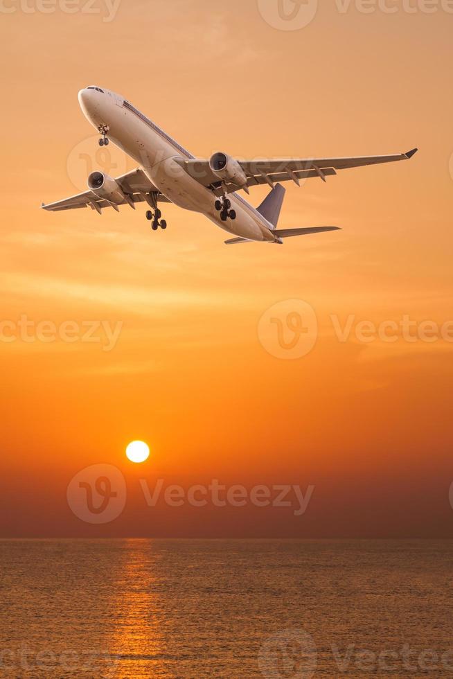 Commercial airplane flying over the sea at sunset photo