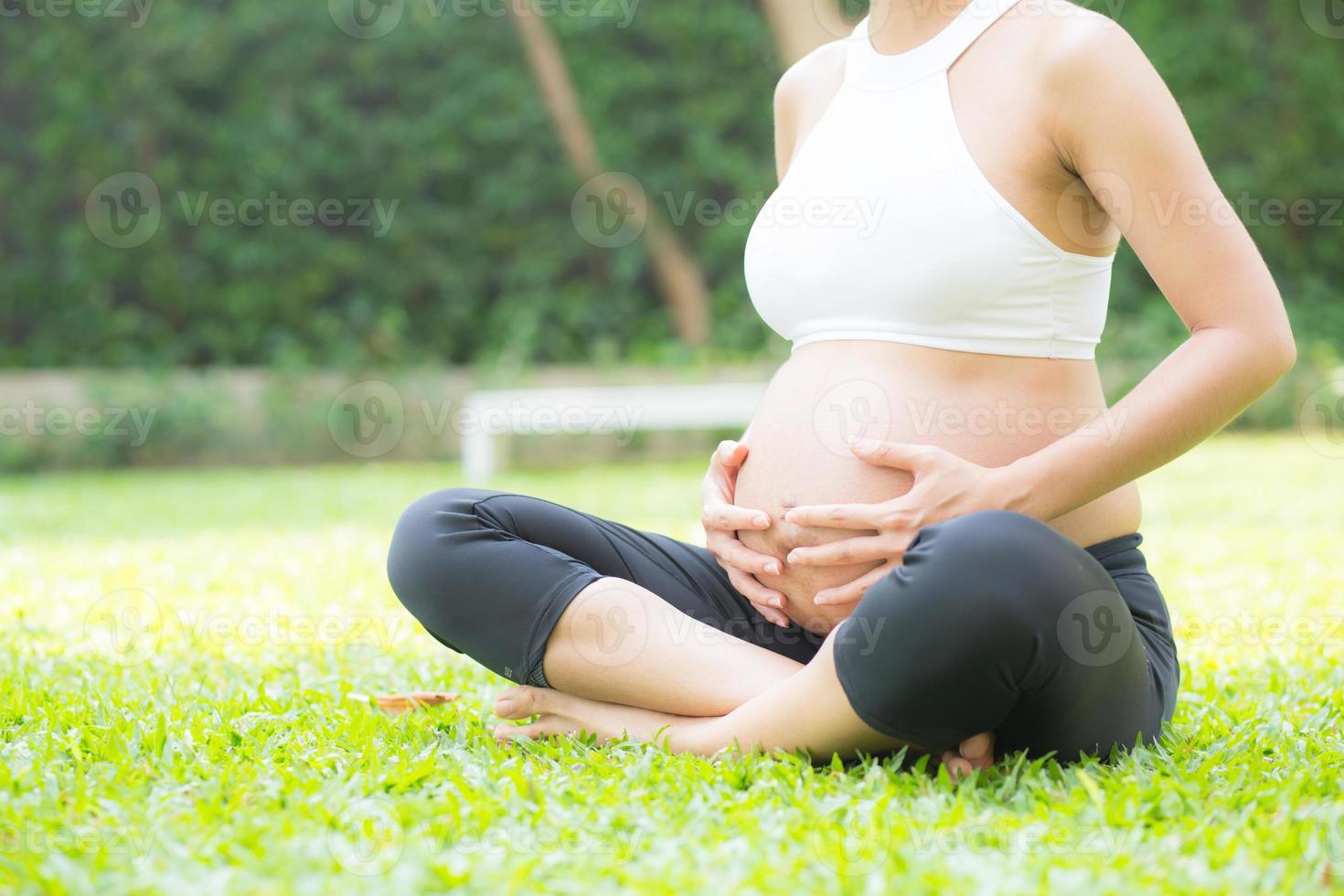 joven asiática está embarazada relajarse en el parque. foto