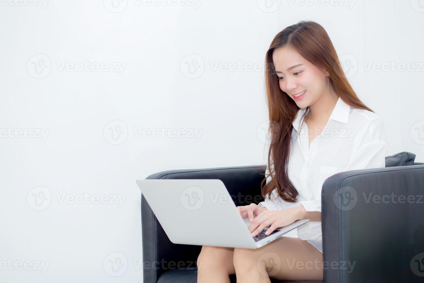 mujer asiática joven que usa la computadora portátil para el ocio en el sofá. foto