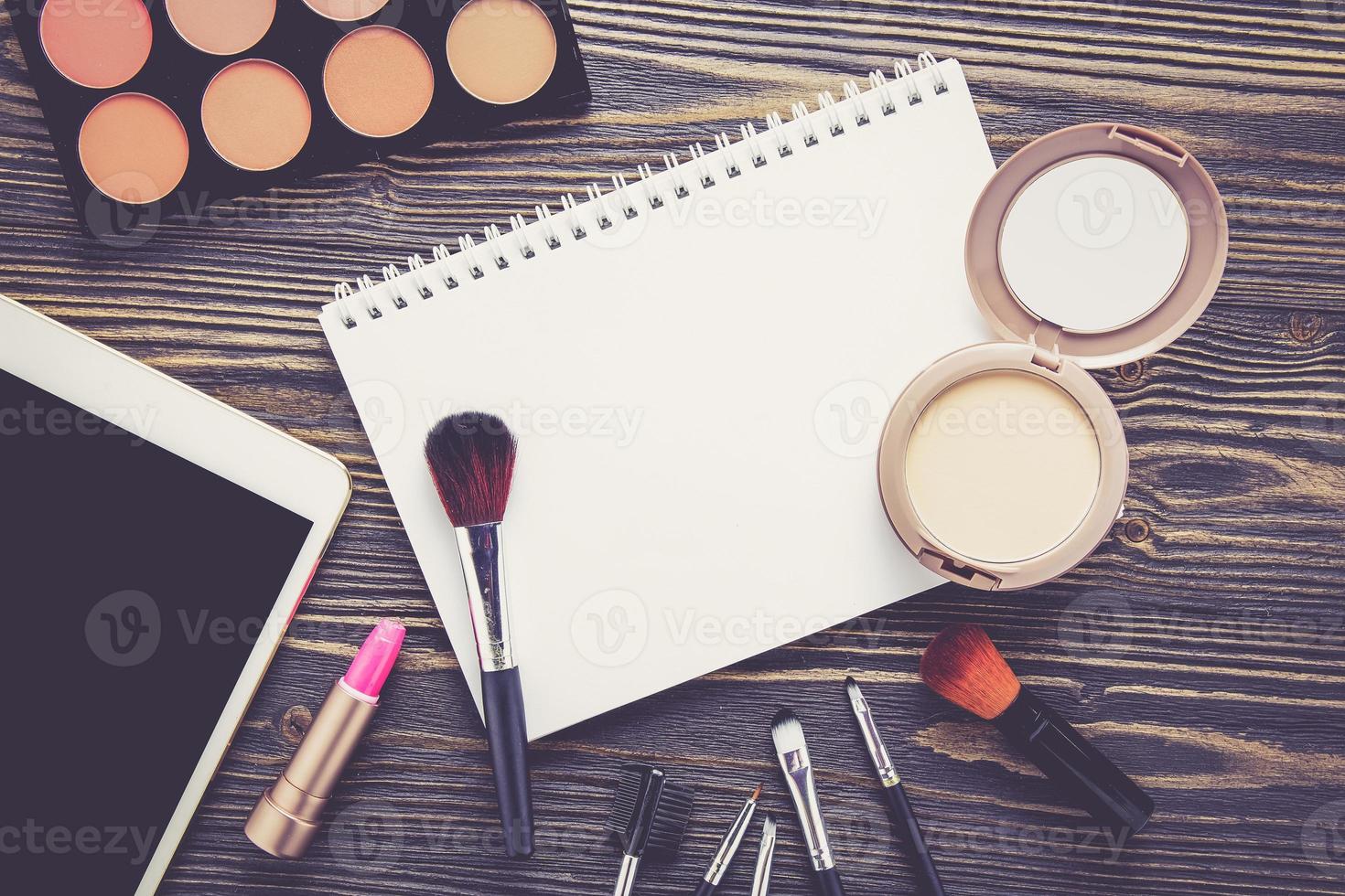 Vista superior de una colección de maquillaje cosmético y cuaderno sobre mesa de madera. foto