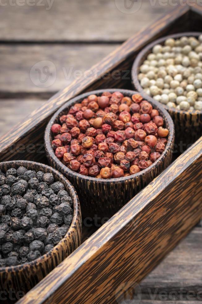 Organic white red and black pepper corns in wood display photo