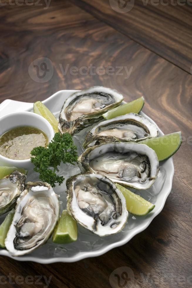 Six fresh oysters with lime wedges and citrus sauce photo