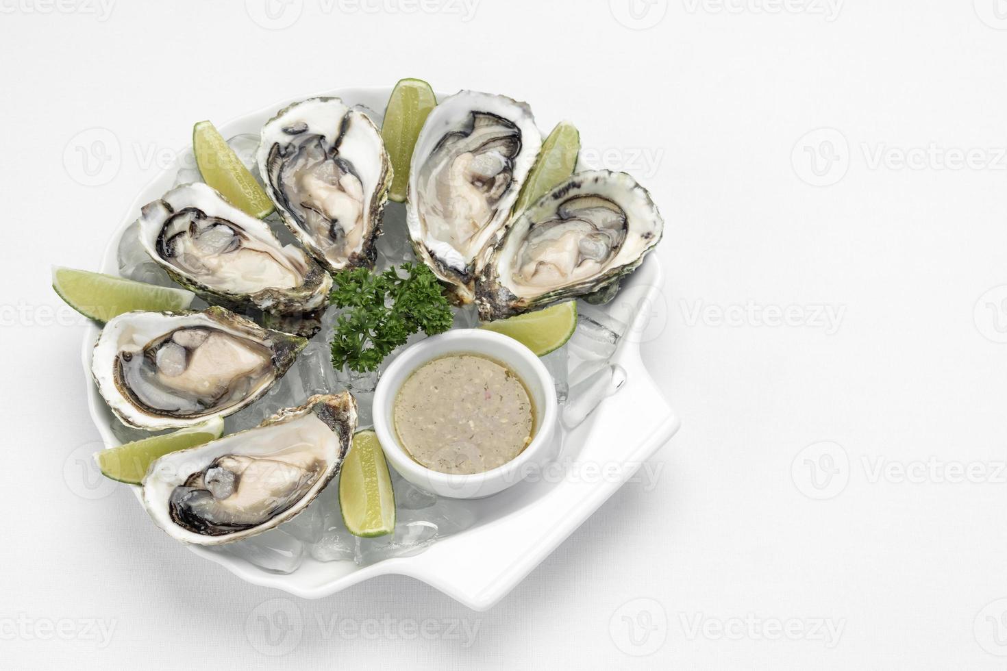 Six fresh oysters with lime wedges and citrus sauce photo