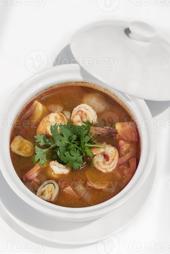 Thai Tom Yum Kung spicy and sour shrimp soup on wood table background in Phuket Thailand photo