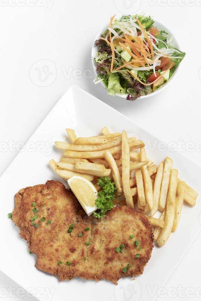 German-breaded pork schnitzel with french fries on white studio background photo