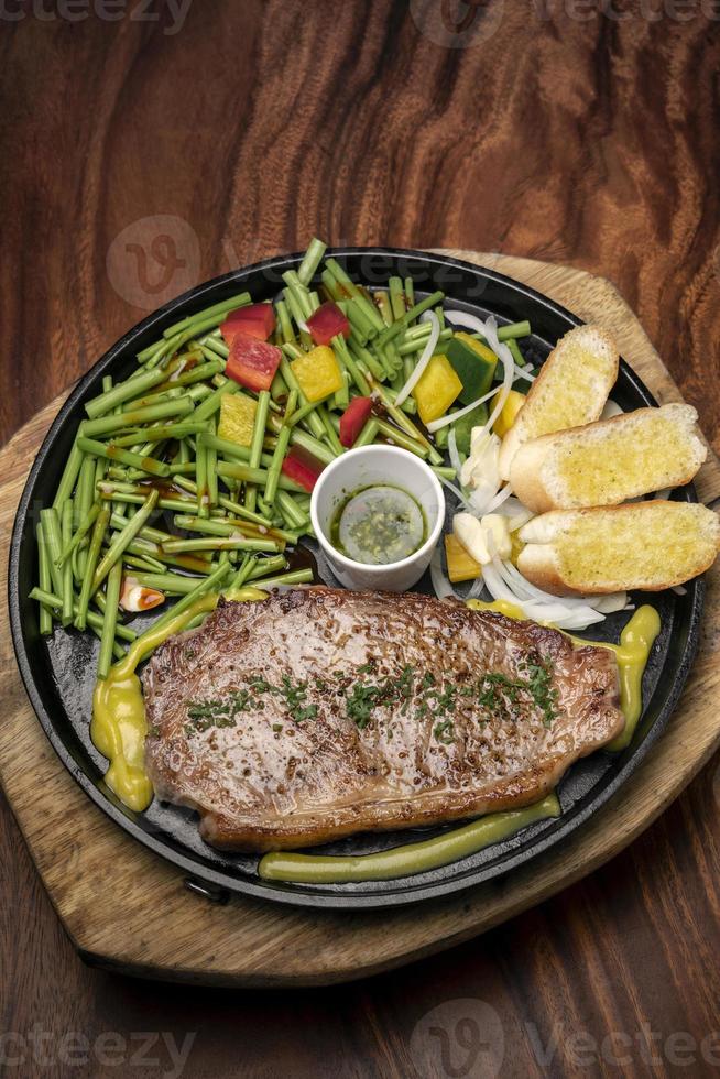 Organic tenderloin beef steak sizzler on hot plate meal platter with mixed vegetables and chimichurri sauce photo