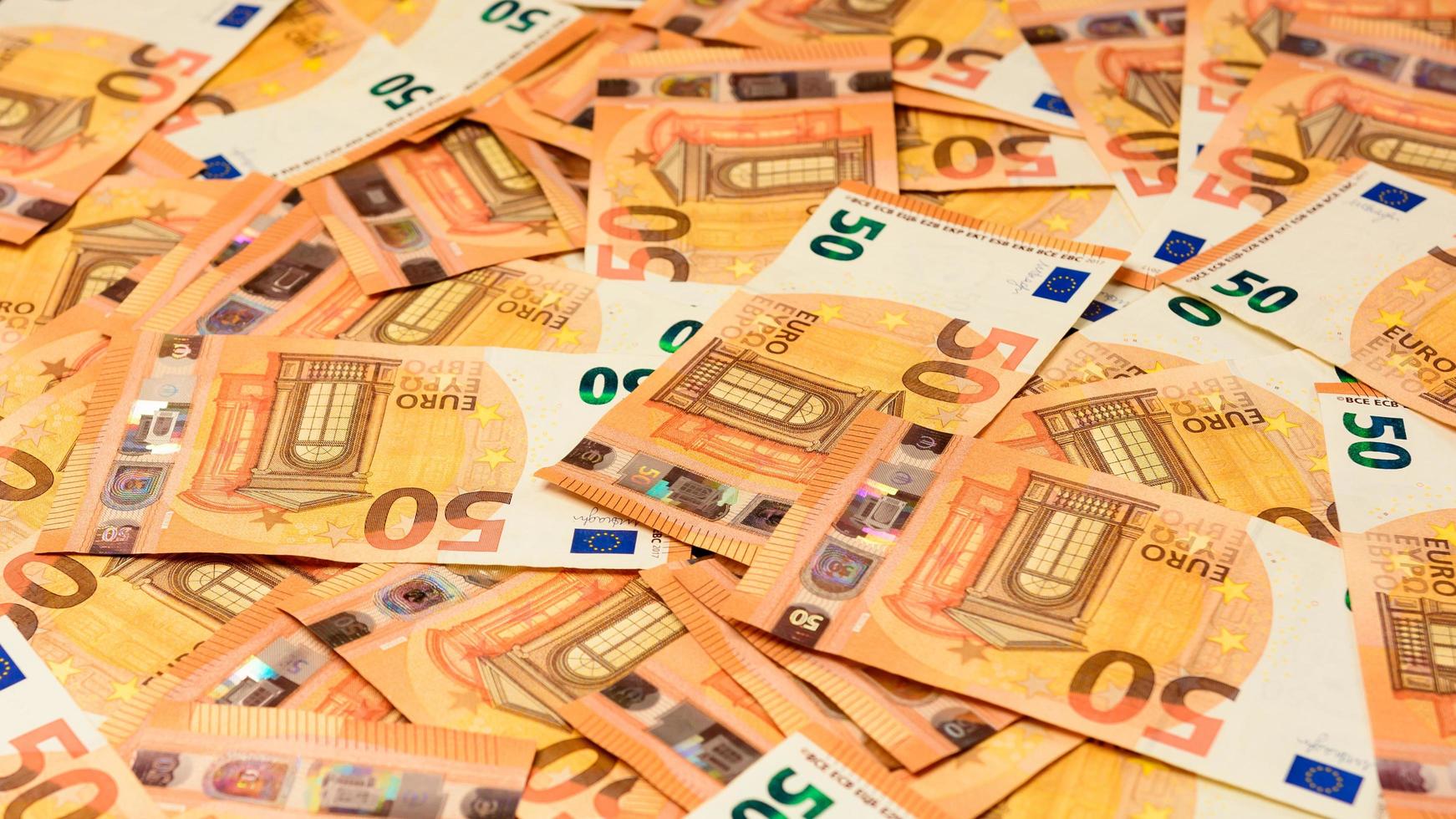 Banknotes in the denomination of 50 euros are scattered randomly photo