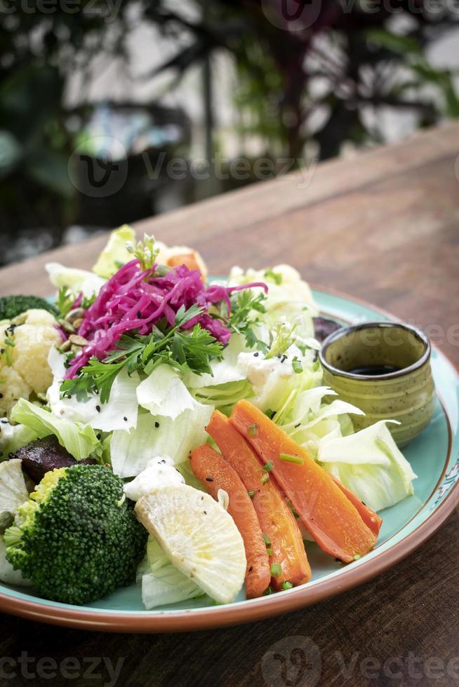 Ensalada rústica con una mezcla saludable de verduras frescas y al vapor en un plato colorido al aire libre en el jardín foto