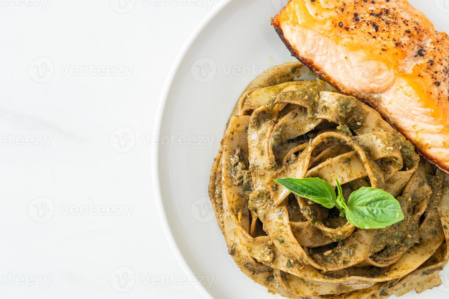 Pasta de espaguetis fettuccine al pesto casero con filete de salmón a la parrilla foto