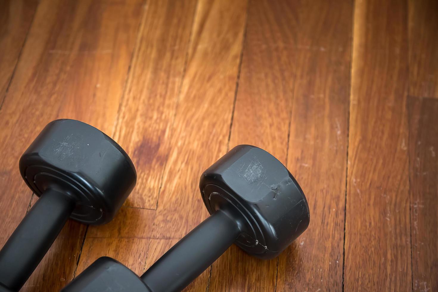 Mancuernas de peso de entrenamiento deportivo sobre suelo de madera foto