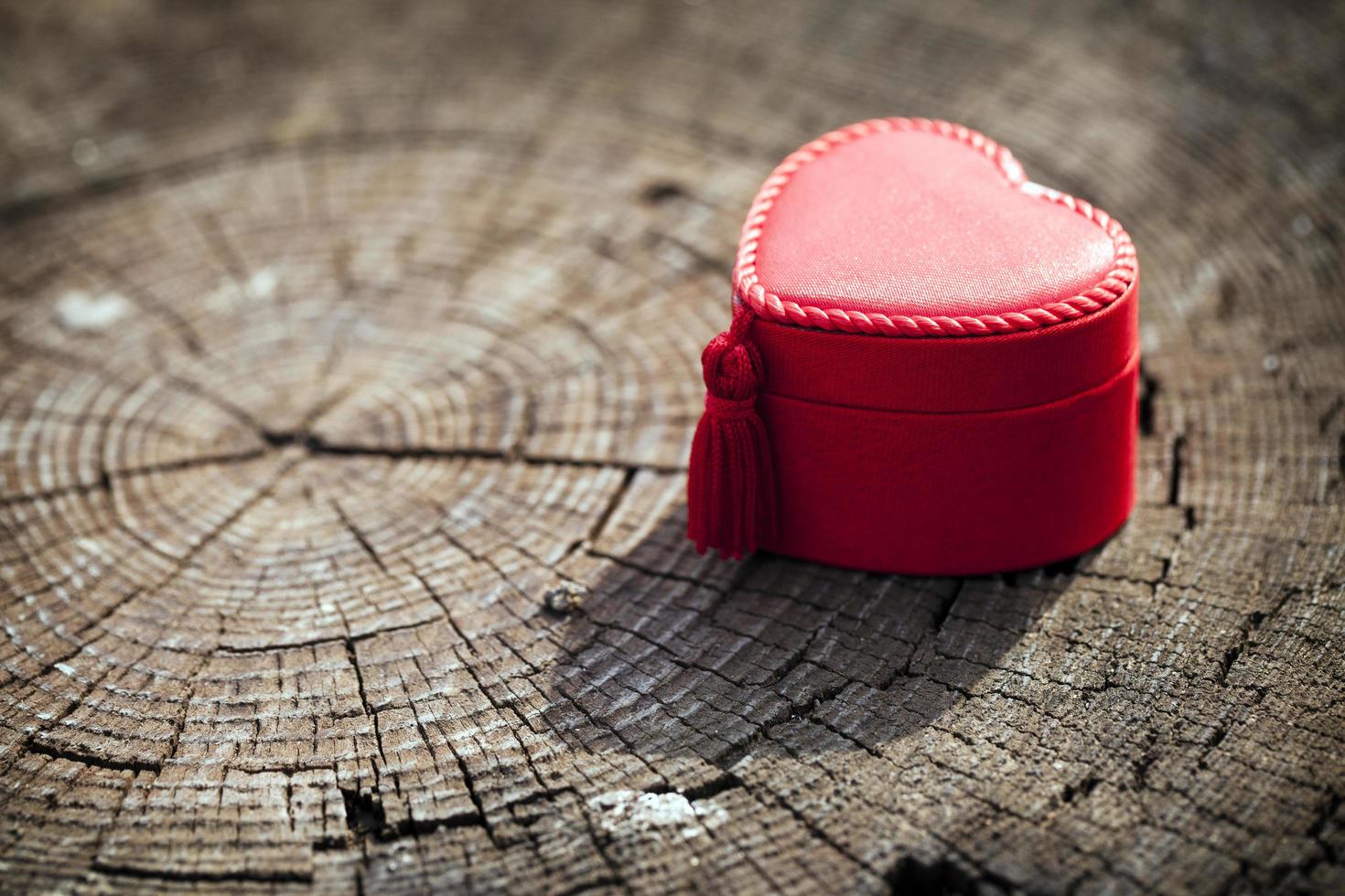 Caja de regalo en forma de corazón sobre tronco de madera foto